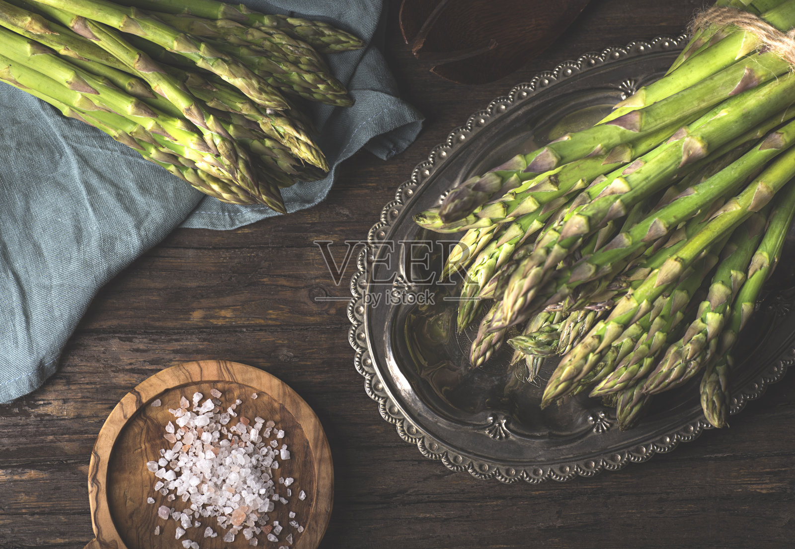 绿色的春天芦笋束在深色的乡村厨房木桌上,平铺着。健康时令食品概念照片摄影图片
