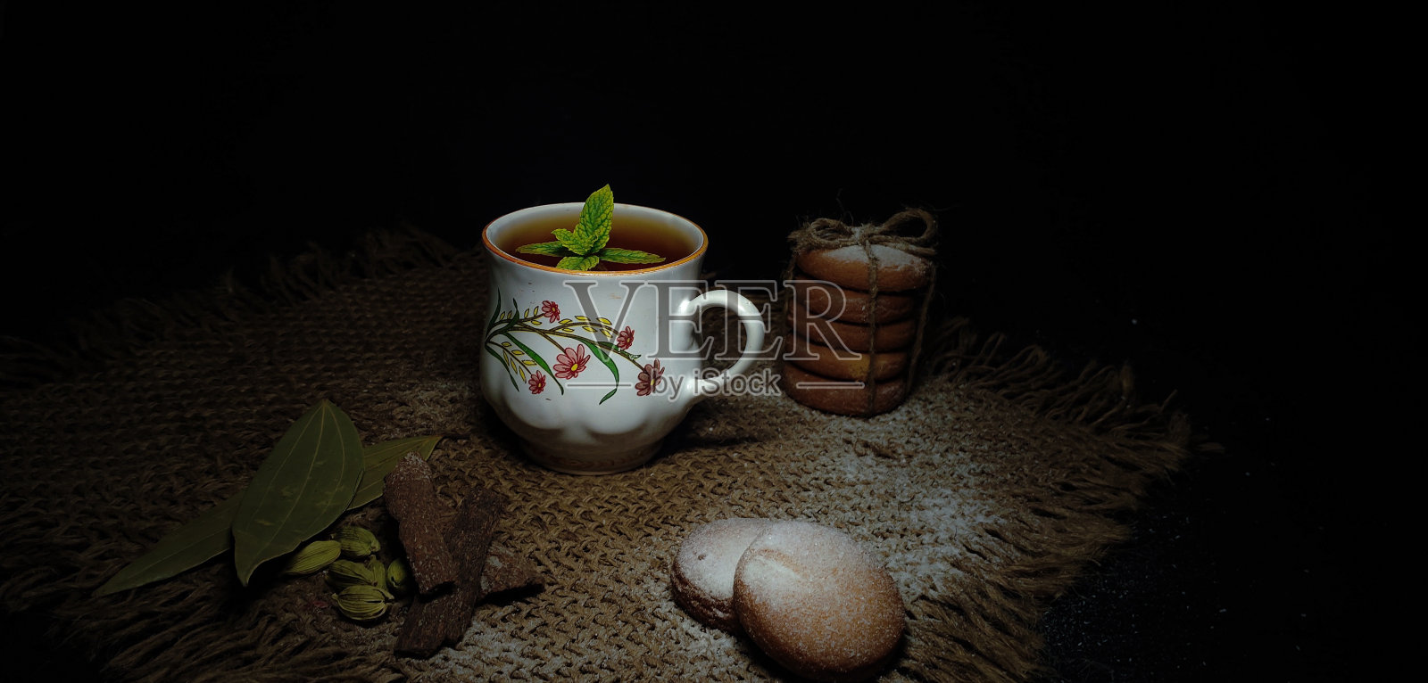 由热茶或咖啡和自制的小甜饼或饼干混合而成,肉桂卷,小豆蔻,月桂叶,隔绝在黑暗的乡村背景中。照片摄影图片