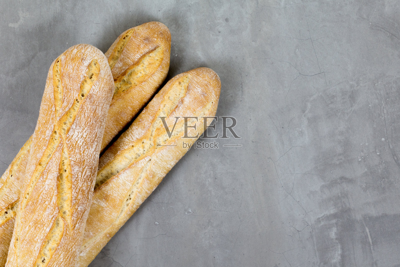 靠近硬面包,烤面包在灰色的石头桌子的背景。法式面包。照片摄影图片