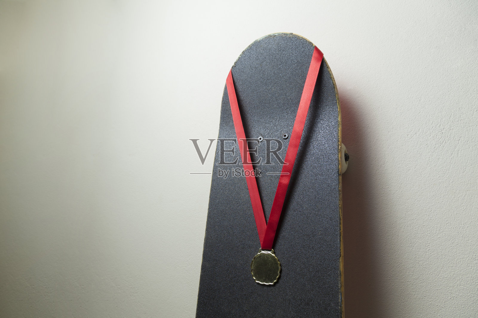 墙上有一块带金牌的滑板。照片摄影图片