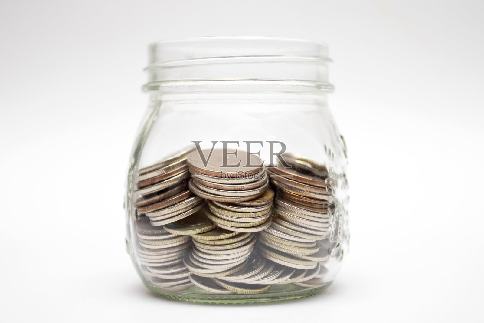 白色背景的玻璃罐里的硬币。省钱的概念照片摄影图片