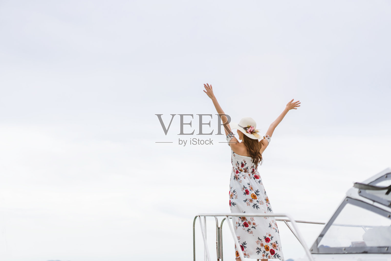 年轻的亚洲独自旅行者女子站在快艇上放松,从后面看张开手臂。照片摄影图片