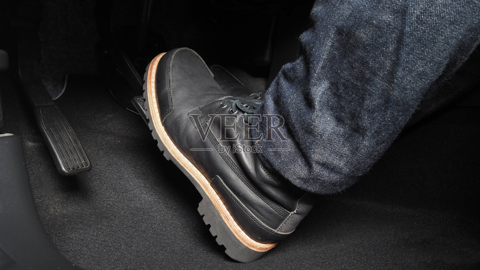 在开车时踩汽车的脚踏板。汽车的油门和刹车踏板。司机驾驶汽车通过推动加速器和刹车踏板的汽车。车辆内部。控制踏板。关闭了。照片摄影图片