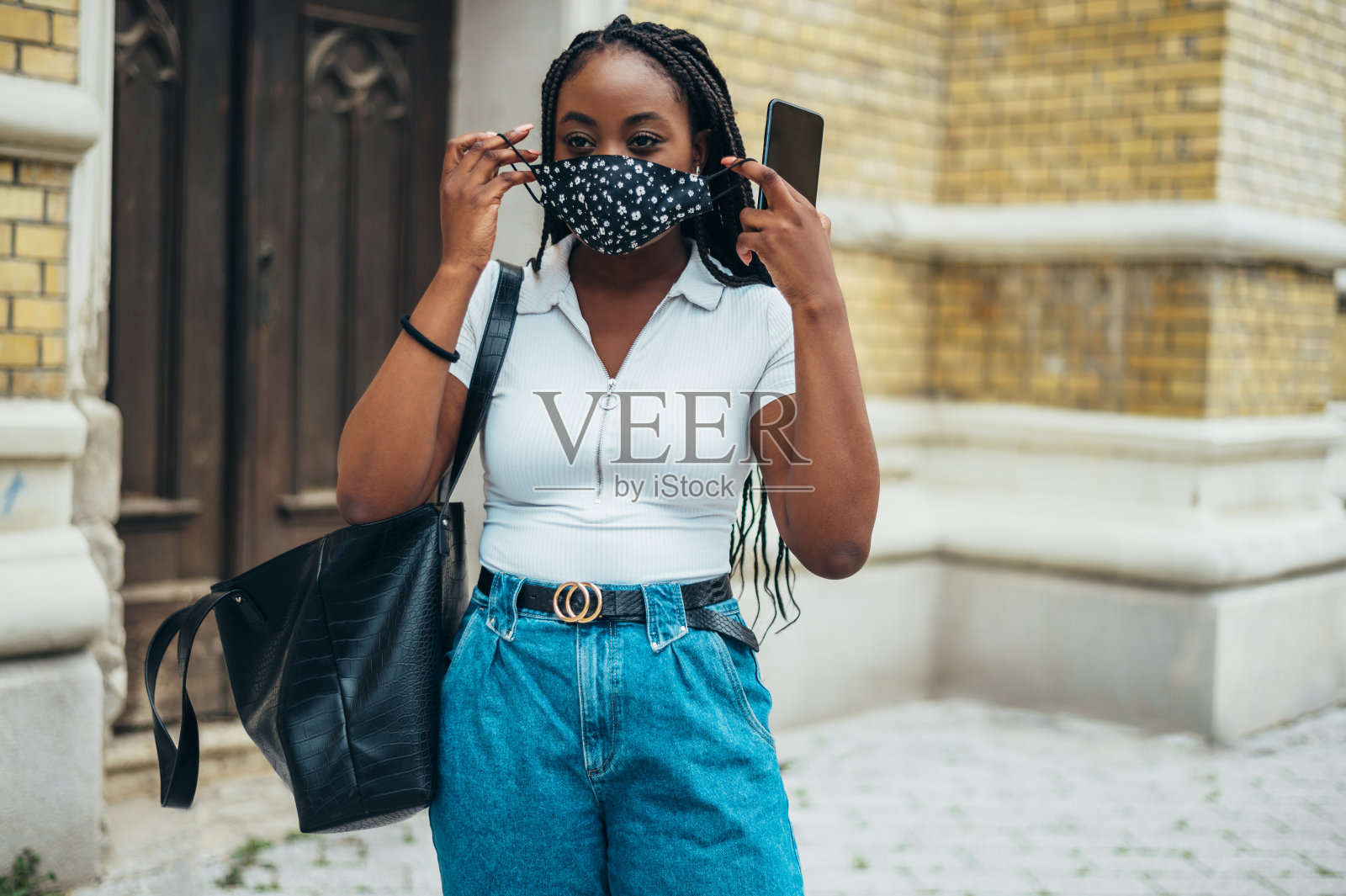 美丽的非洲裔美国女人拿着智能手机戴着防护面具照片摄影图片