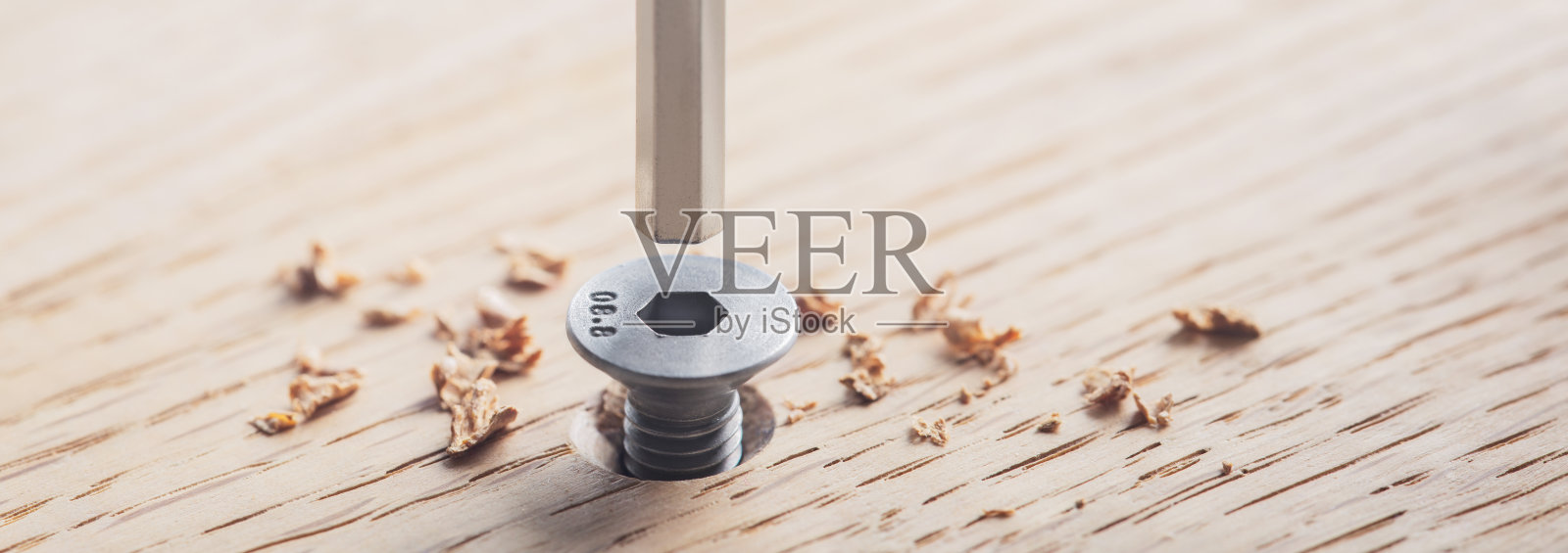 六角螺栓螺钉用六角扳手安装在橡木板上。扳手、螺栓、螺钉和螺母。照片摄影图片