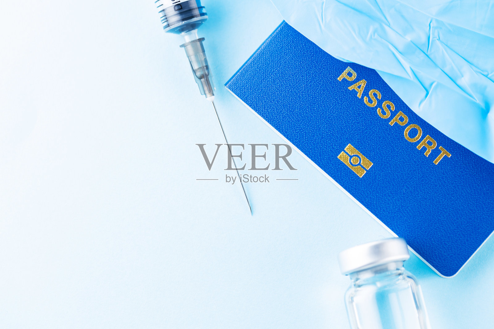 接种疫苗的概念。国际生物识别疫苗接种护照、疫苗瓶和注射器。疫苗瓶,注射器和蓝色背景的护照。免疫的护照照片摄影图片