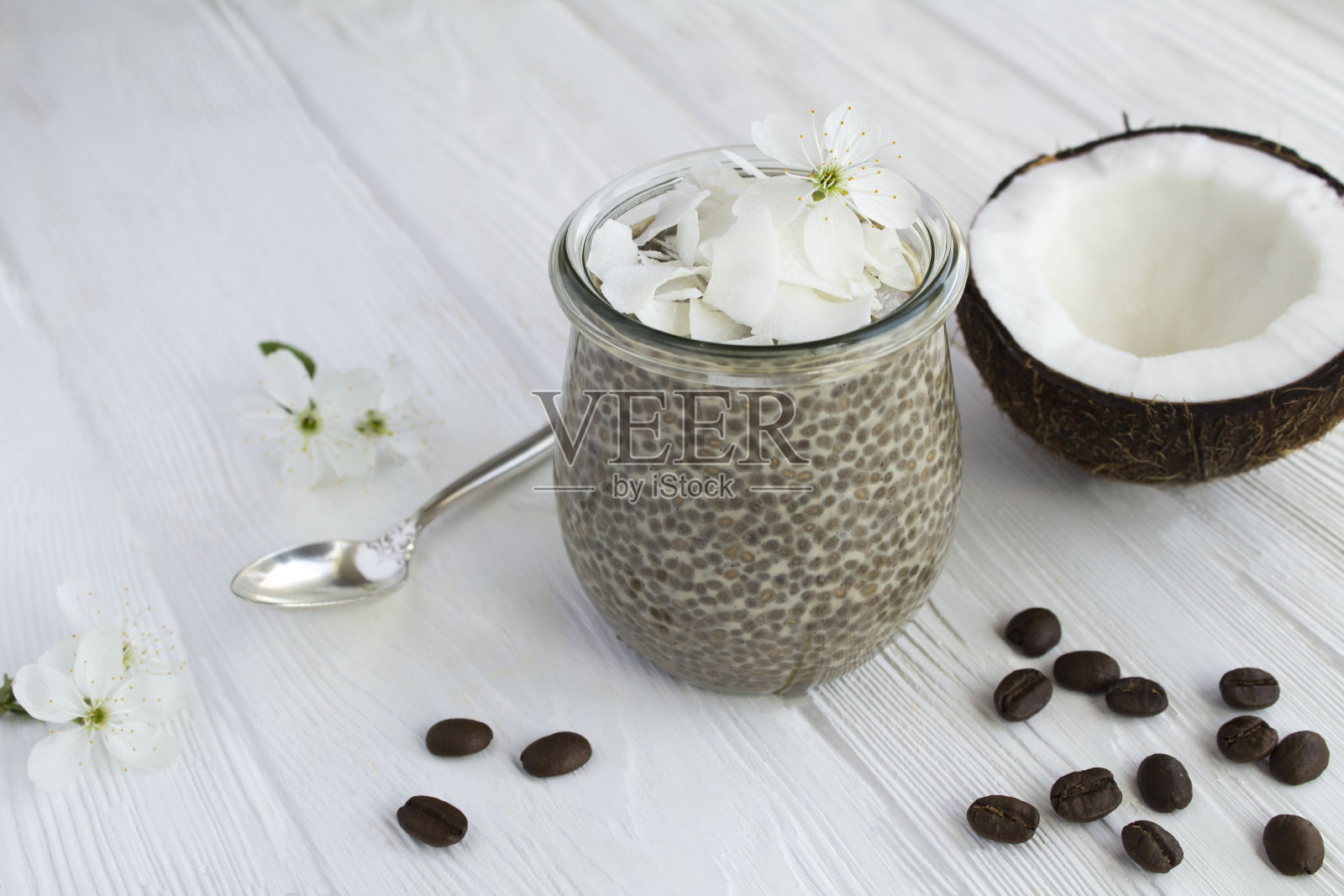 咖啡布丁与奇亚籽和椰子片的玻璃罐在白色的木制背景照片摄影图片