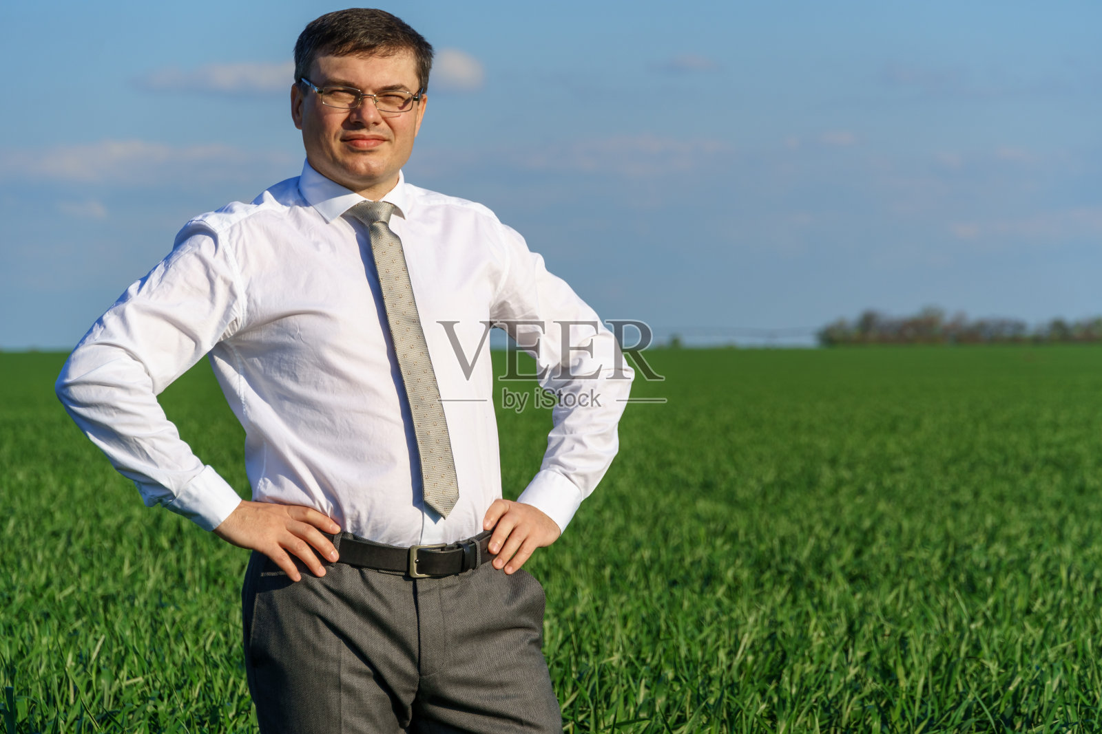商人在野外摆姿势,他望着远方休息,绿色的草地和蓝色的天空作为背景照片摄影图片