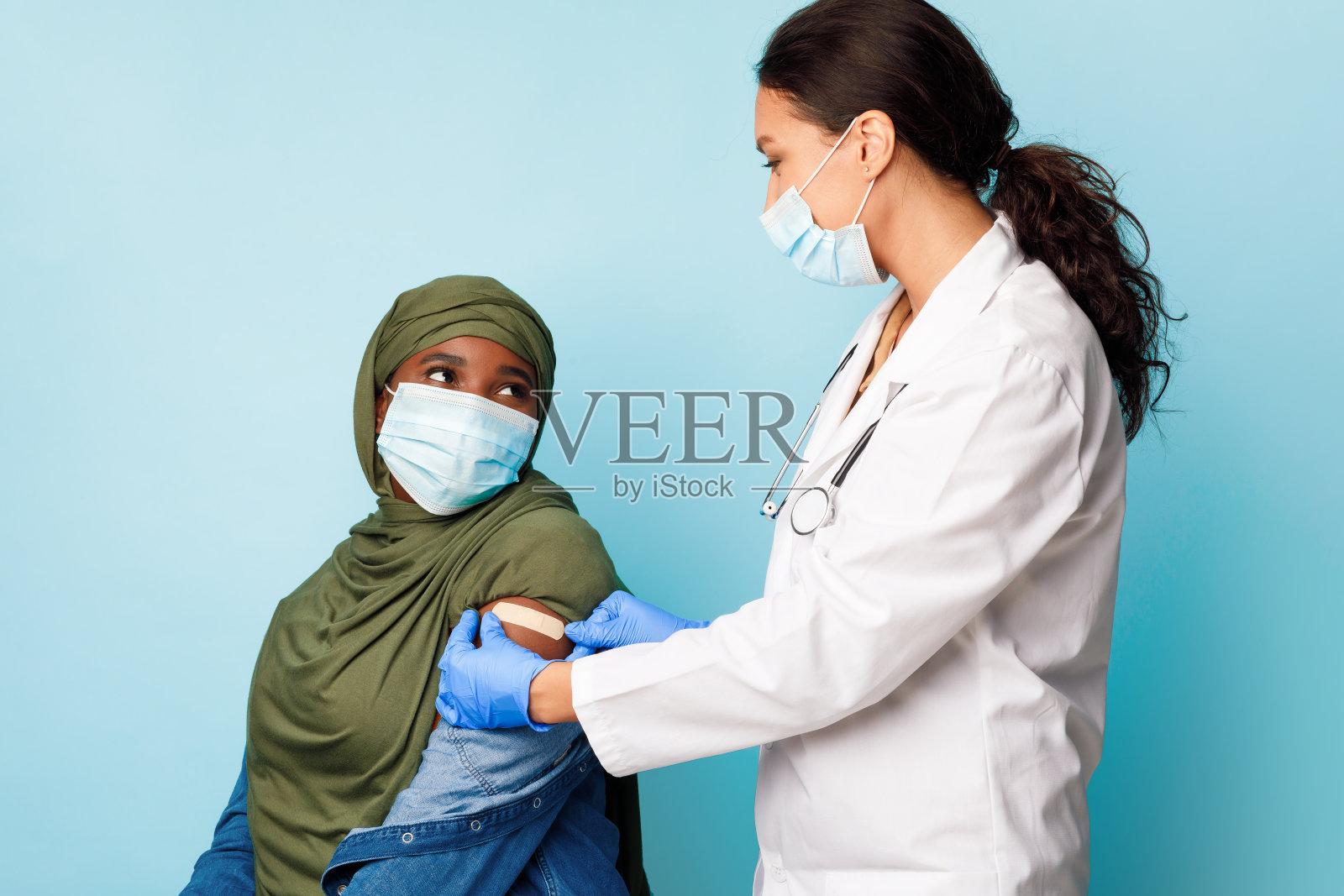 医生注射疫苗后应用绷带黑色穆斯林女士,工作室照片摄影图片