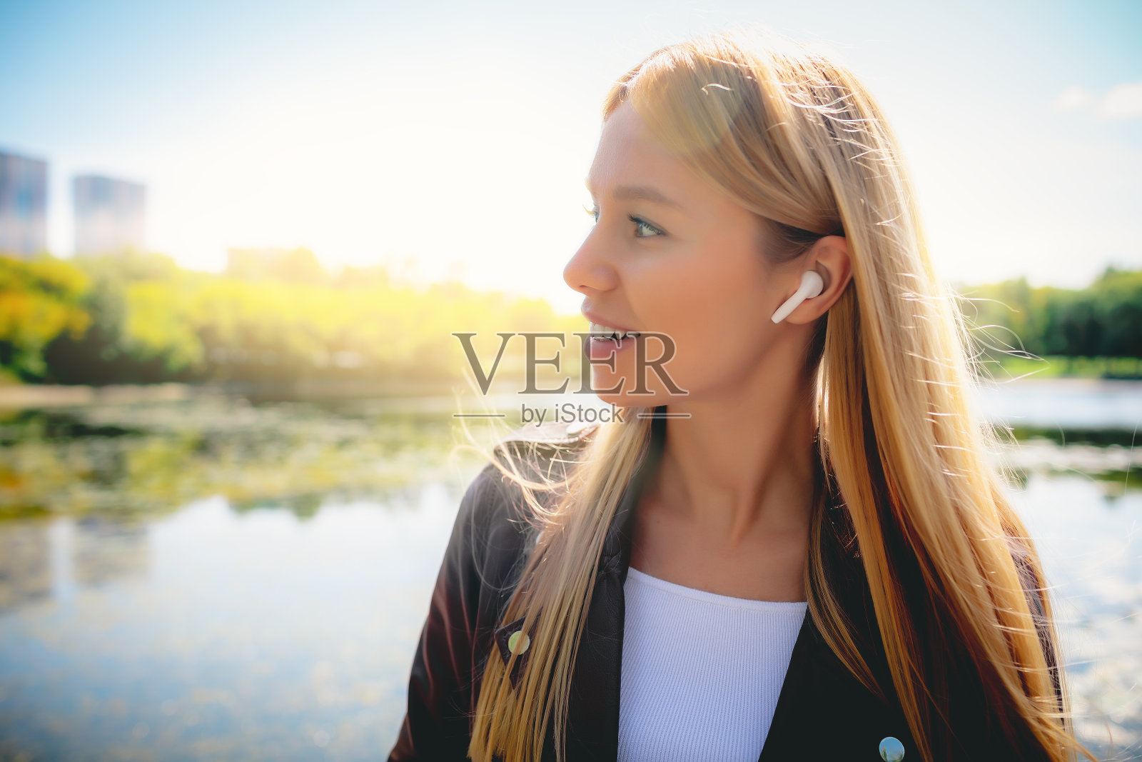 迷人的女孩用她的手机,无线耳机在公园里跑步照片摄影图片