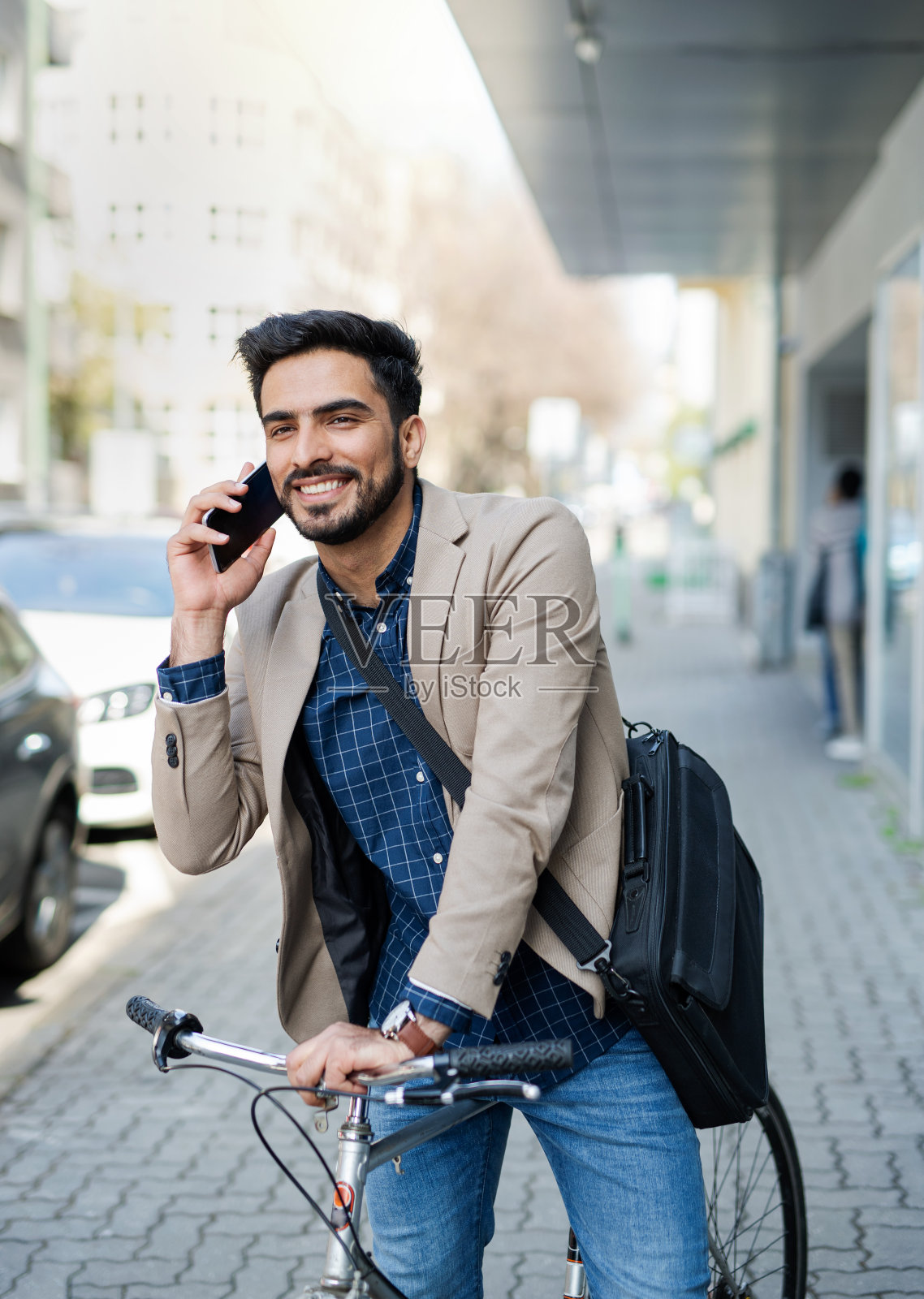 骑自行车和使用智能手机在城市户外工作的年轻商务男士照片摄影图片