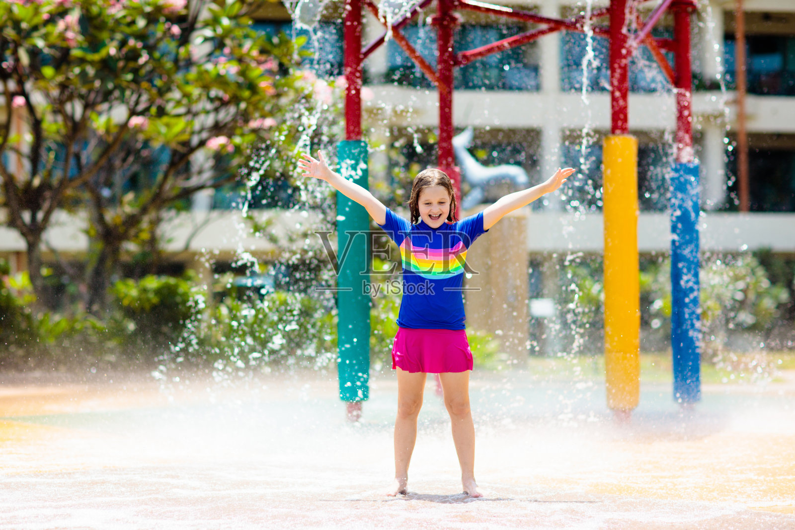 孩子在水上乐园的小桶下玩耍。照片摄影图片