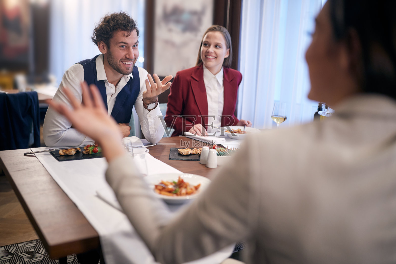 一群朋友在餐厅吃午饭,谈笑风生。照片摄影图片