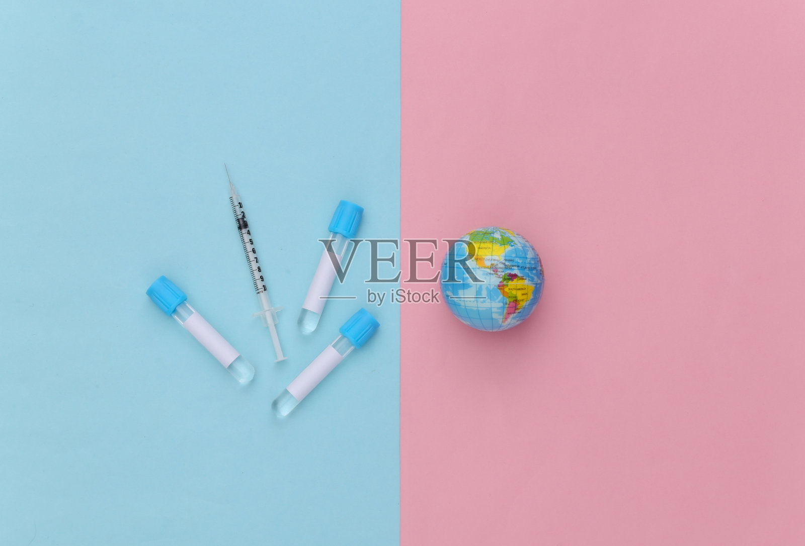 带注射器的医用试管,蓝粉色背景上的地球仪。接种疫苗。俯视图照片摄影图片