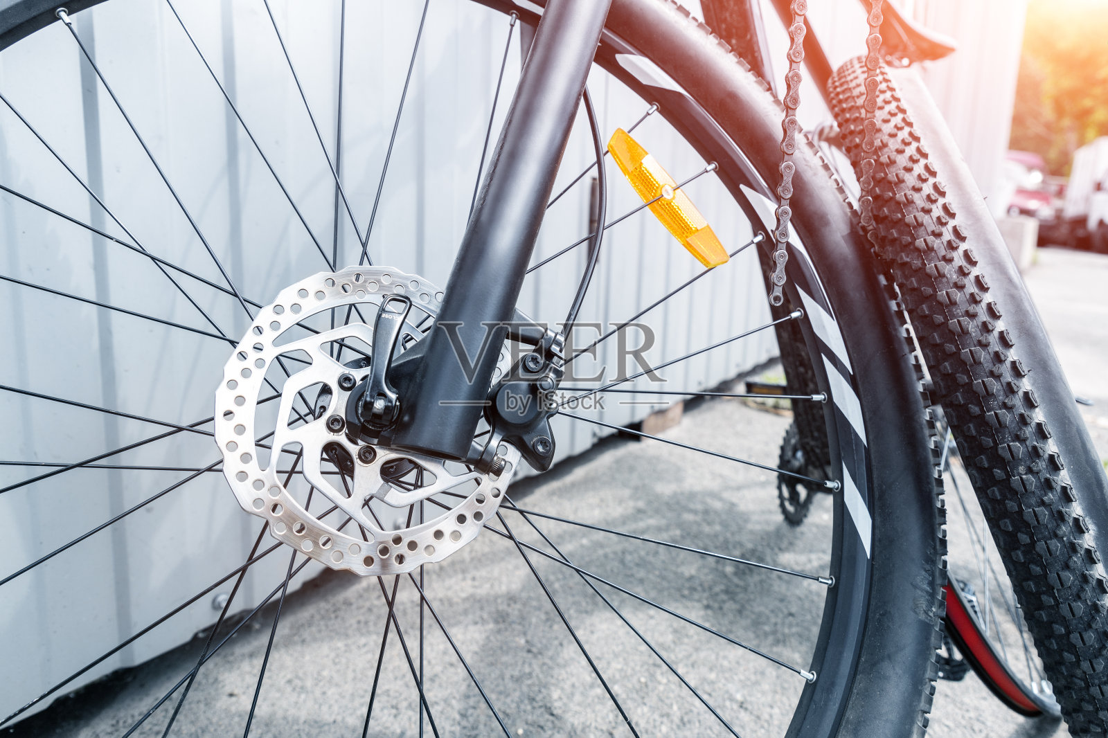 在户外修理厂固定站,用拆下的车轮和轮胎拆卸黑色碳纤维自行车的特写细节。部分运动轻型自行车在城市街道上照片摄影图片