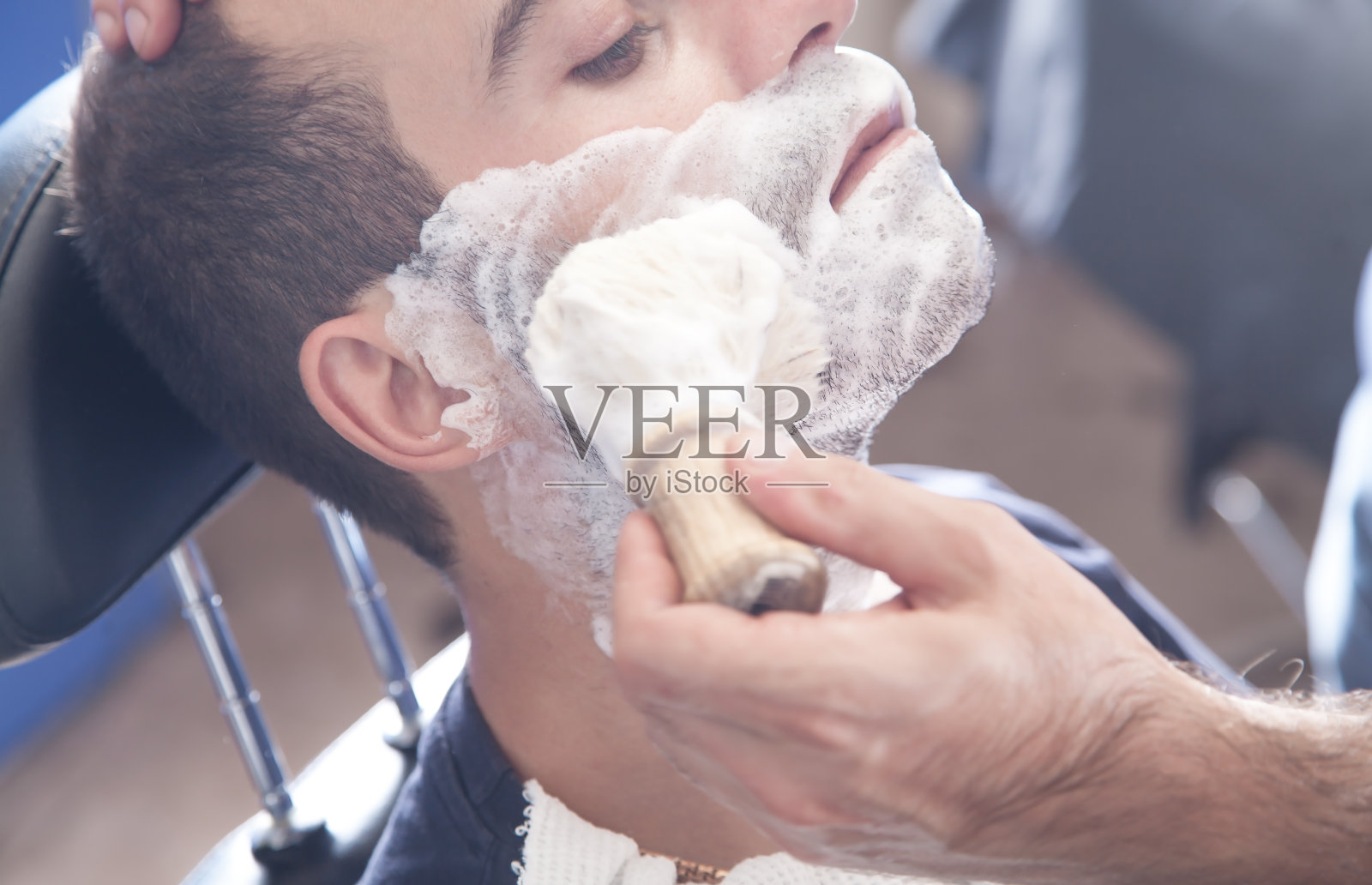 理发师涂抹剃须膏。照片摄影图片