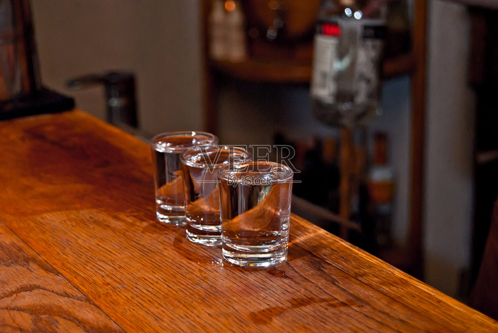吧台上放着伏特加的透明玻璃杯。桌上放着几杯伏特加。满杯的杯子会排成一排。照片摄影图片