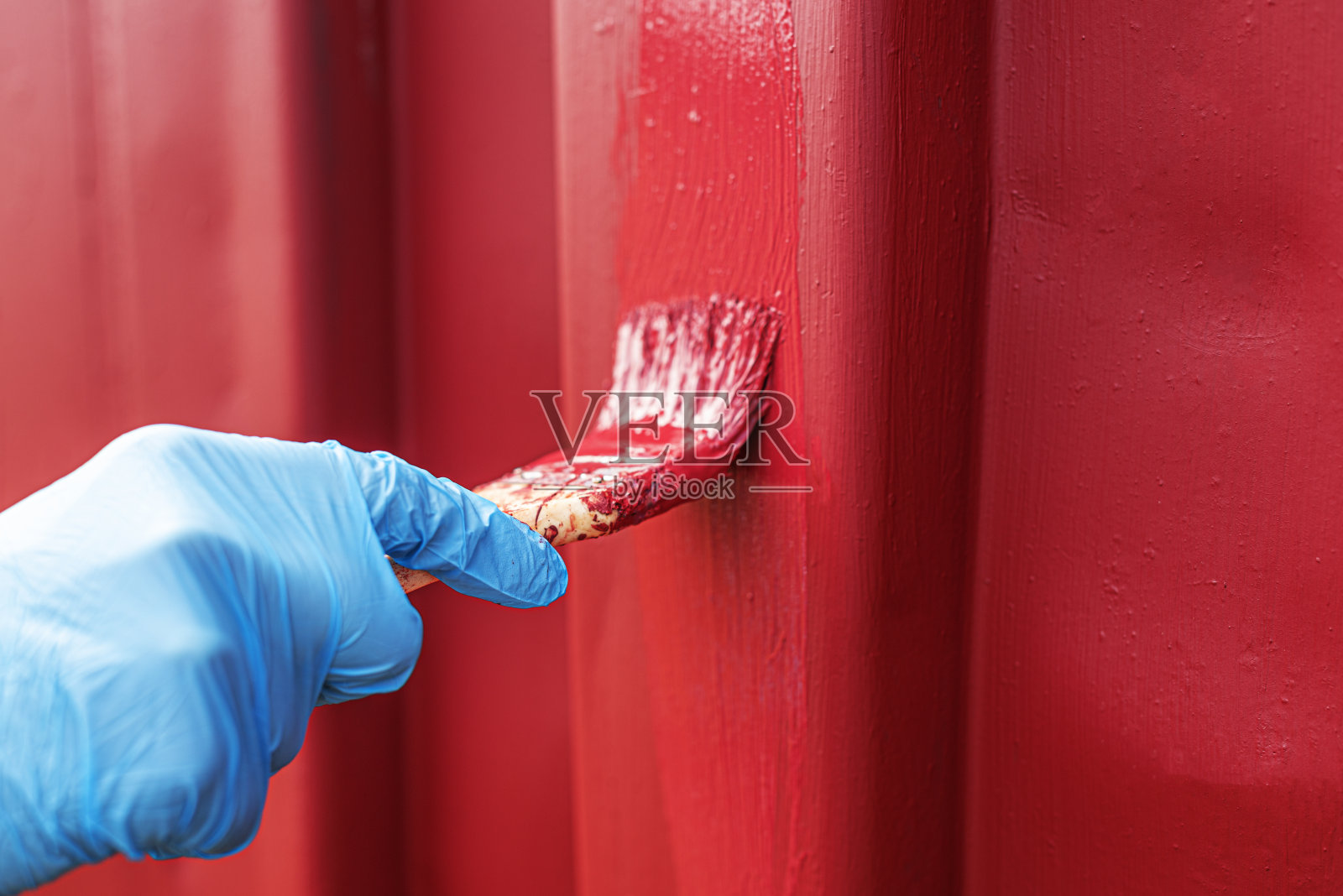 一只手戴着手套画一个表面。照片摄影图片