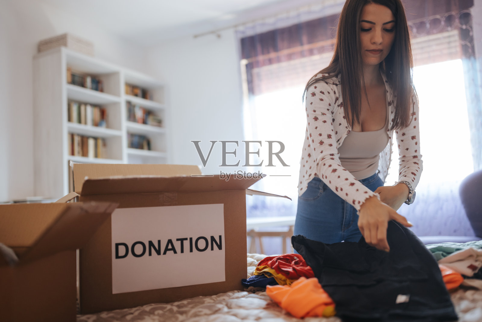 漂亮的年轻女子在家里把衣服装进捐赠箱照片摄影图片