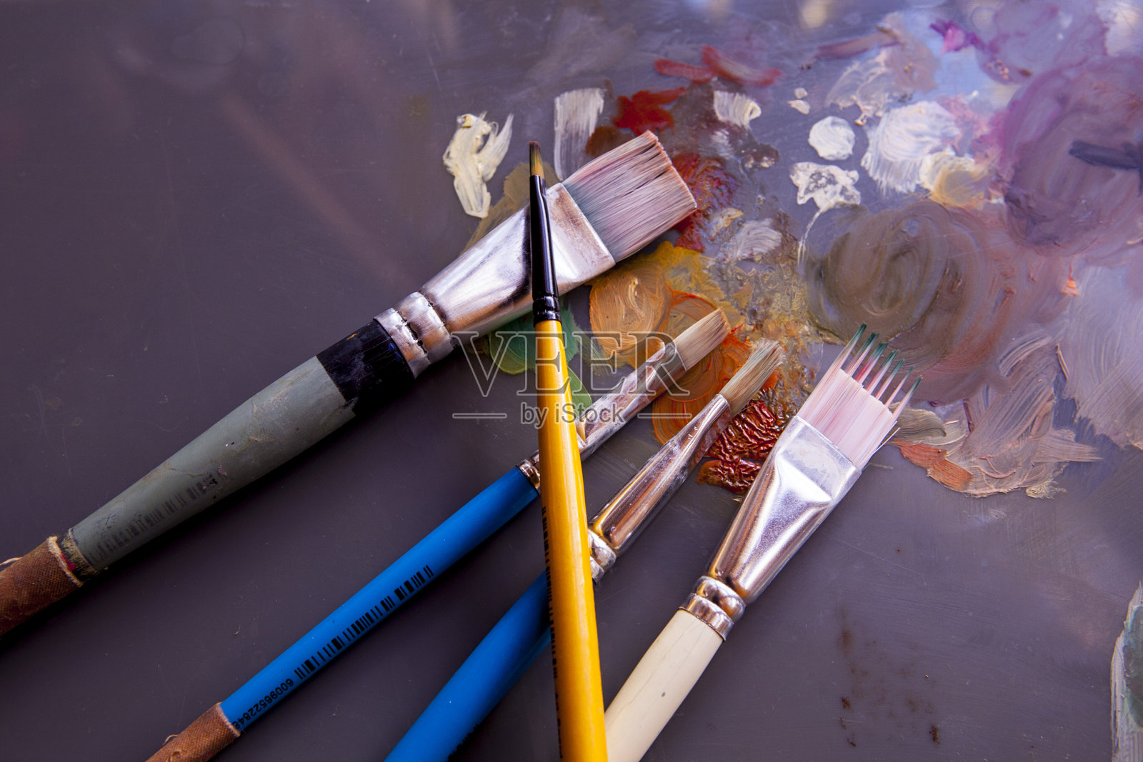 用画笔在画家的调色板上画颜料。照片摄影图片