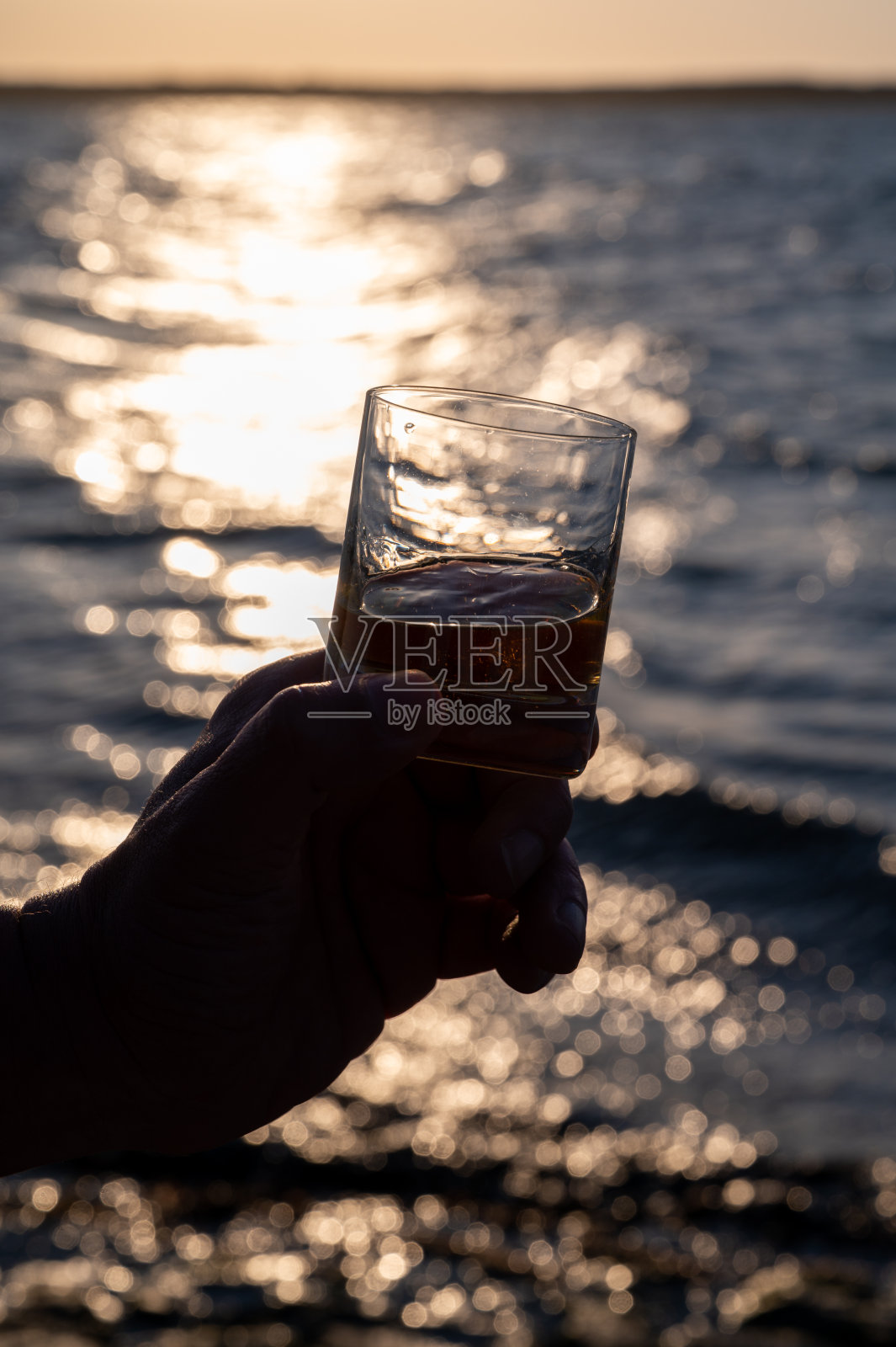 喝单一麦芽苏格兰威士忌日落与海洋或河的观点,私人威士忌旅游在苏格兰,英国照片摄影图片