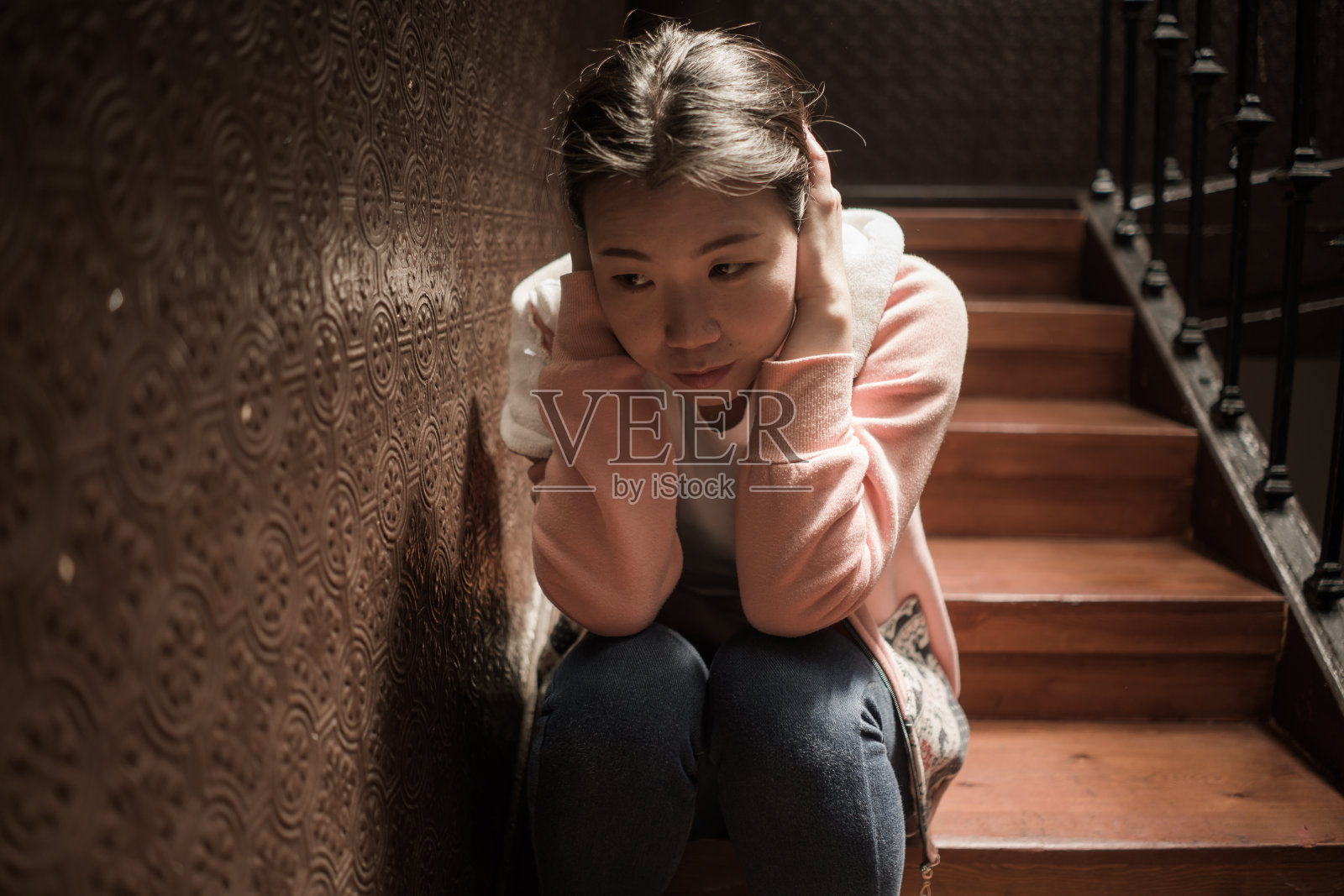 痛苦的年轻亚裔女子:楼梯上的抑郁肖像照片摄影图片