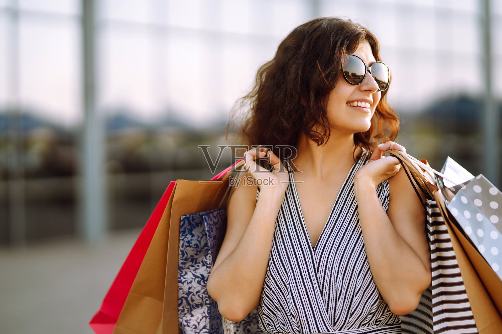 年轻女子购物后拿着购物袋走在街上。照片摄影图片