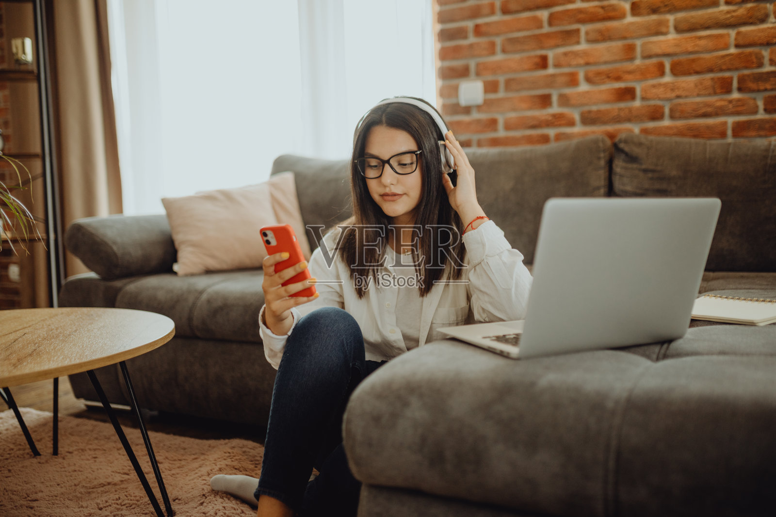 一位年轻的女学生坐在沙发上使用笔记本电脑耳机学习照片摄影图片