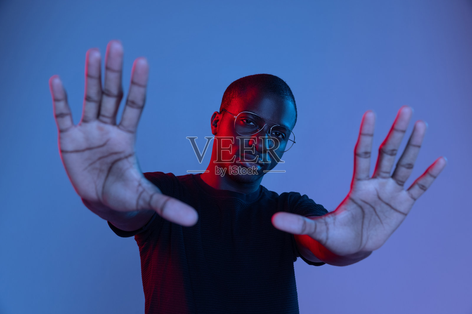 年轻的非洲英俊男子的肖像,摆出孤立的黑色背景在混合霓虹灯。照片摄影图片