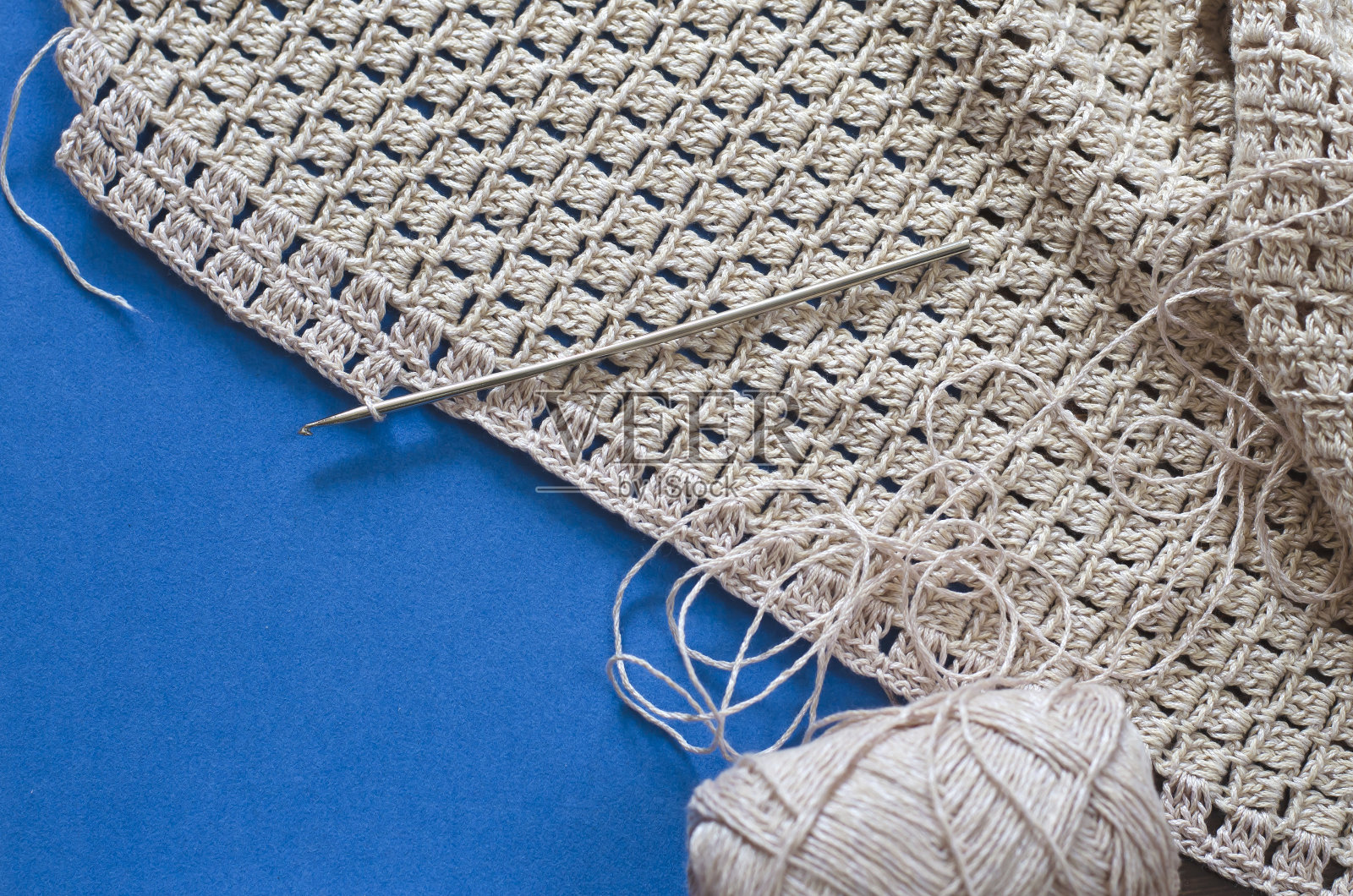 钩针与米色棉线在蓝色的背景。照片摄影图片