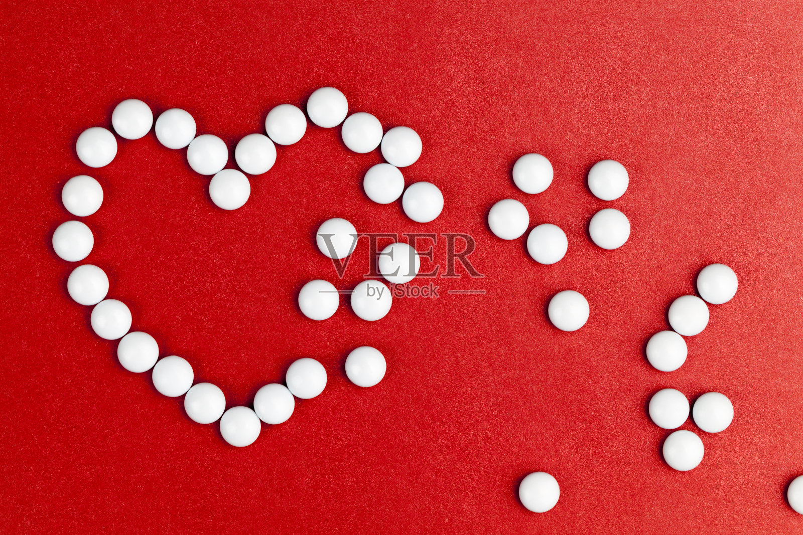 堆放在红色心脏形状背景上的药片照片摄影图片