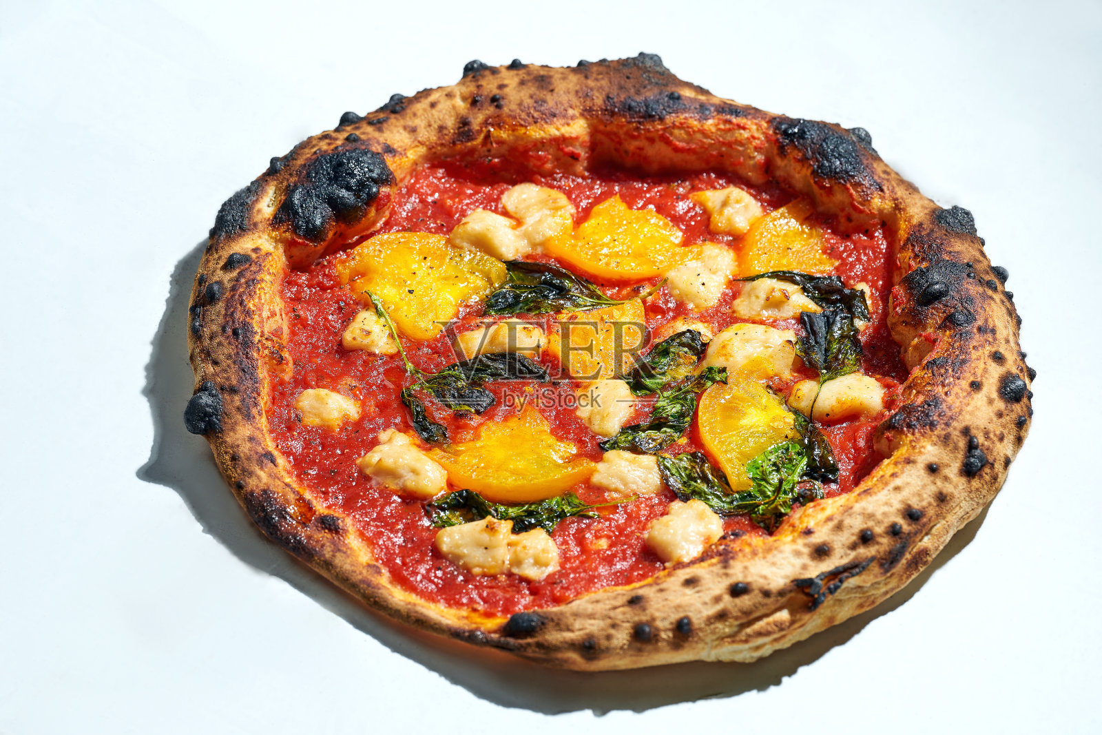 美味的意大利烧木披萨,配上番茄酱,黄色的番茄和素食芝士,在灰色的背景上。硬光。照片摄影图片