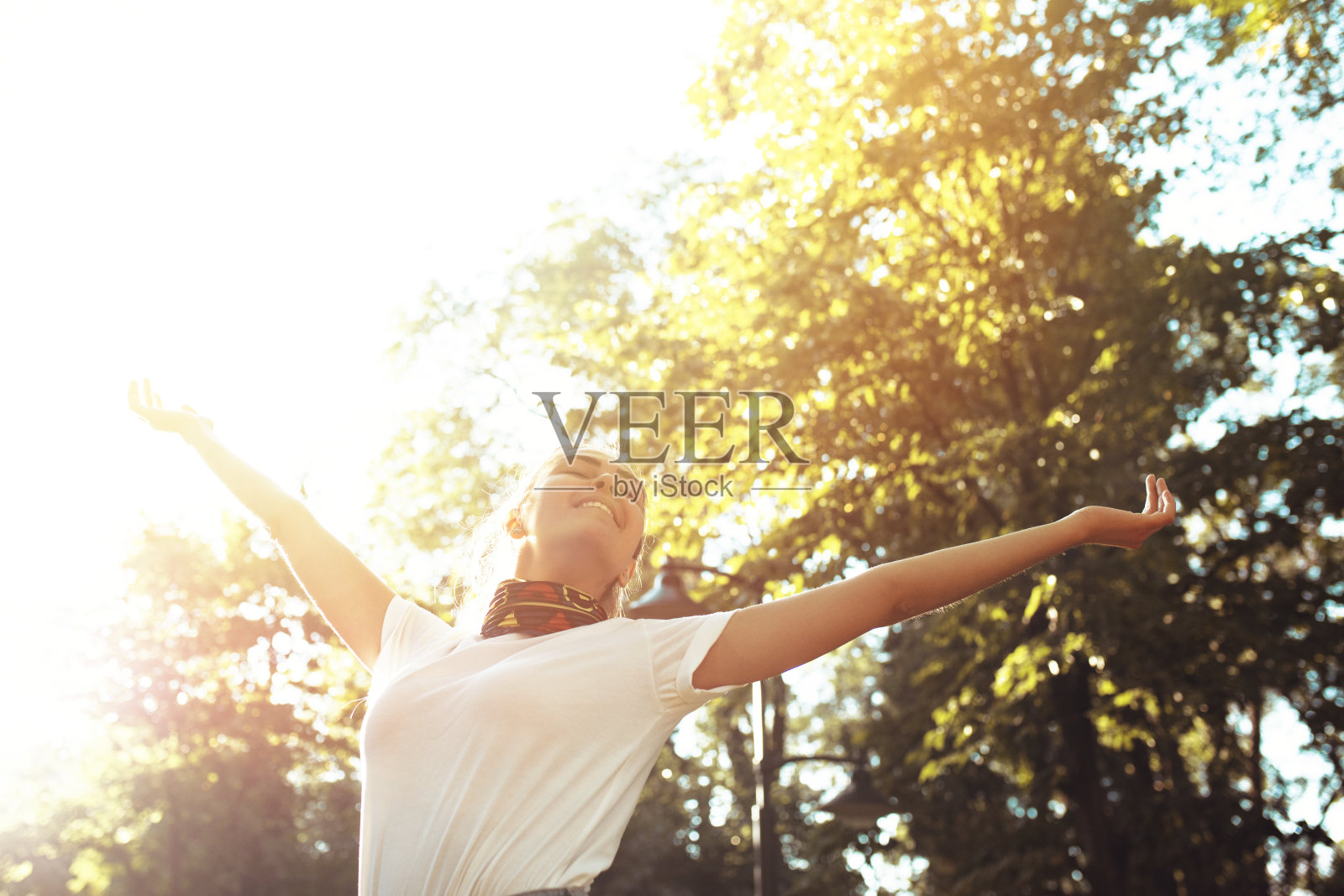 在公园里,漂亮的年轻女子双臂高高地举向天空,享受夏天照片摄影图片