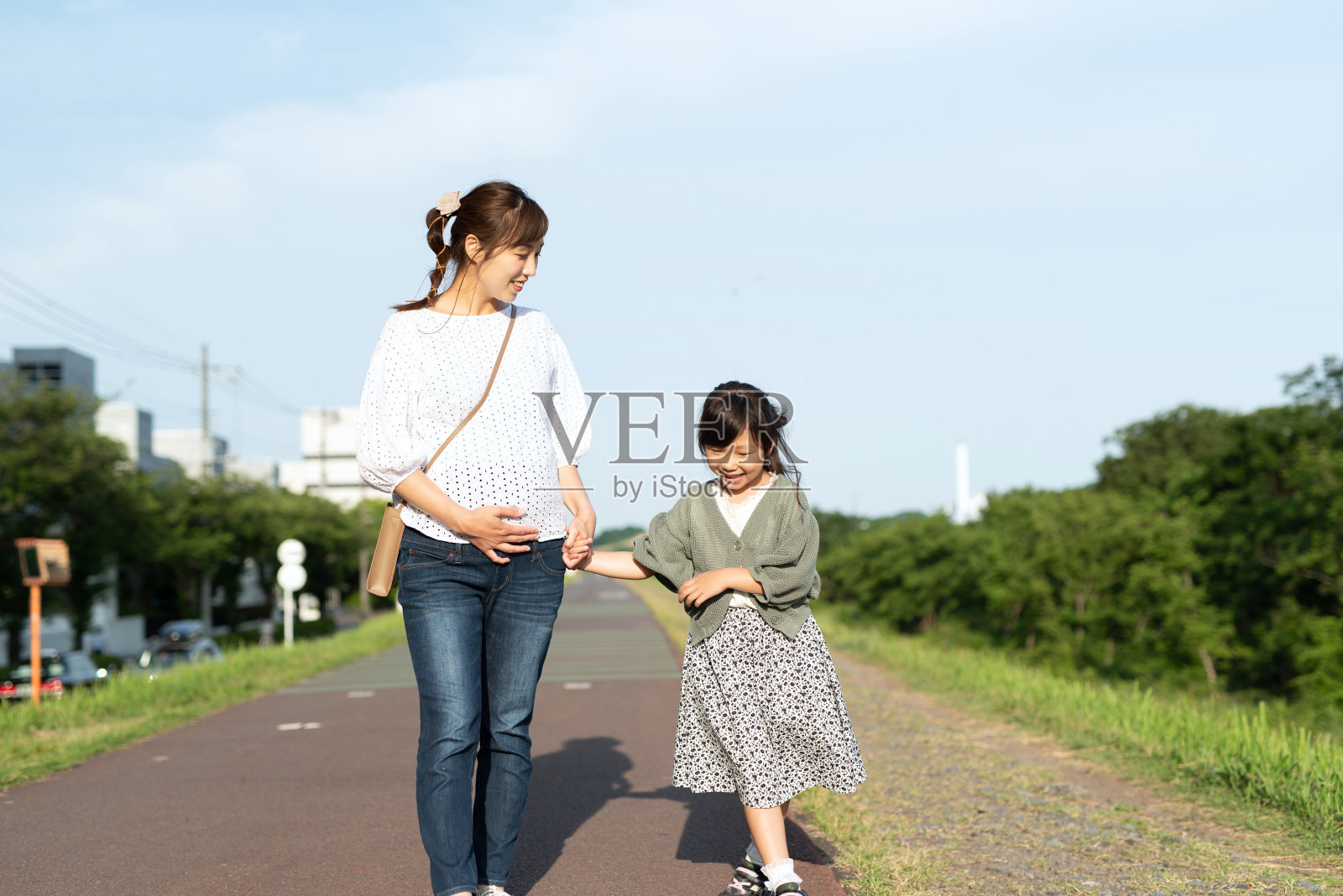女儿和怀孕的母亲边走边聊照片摄影图片
