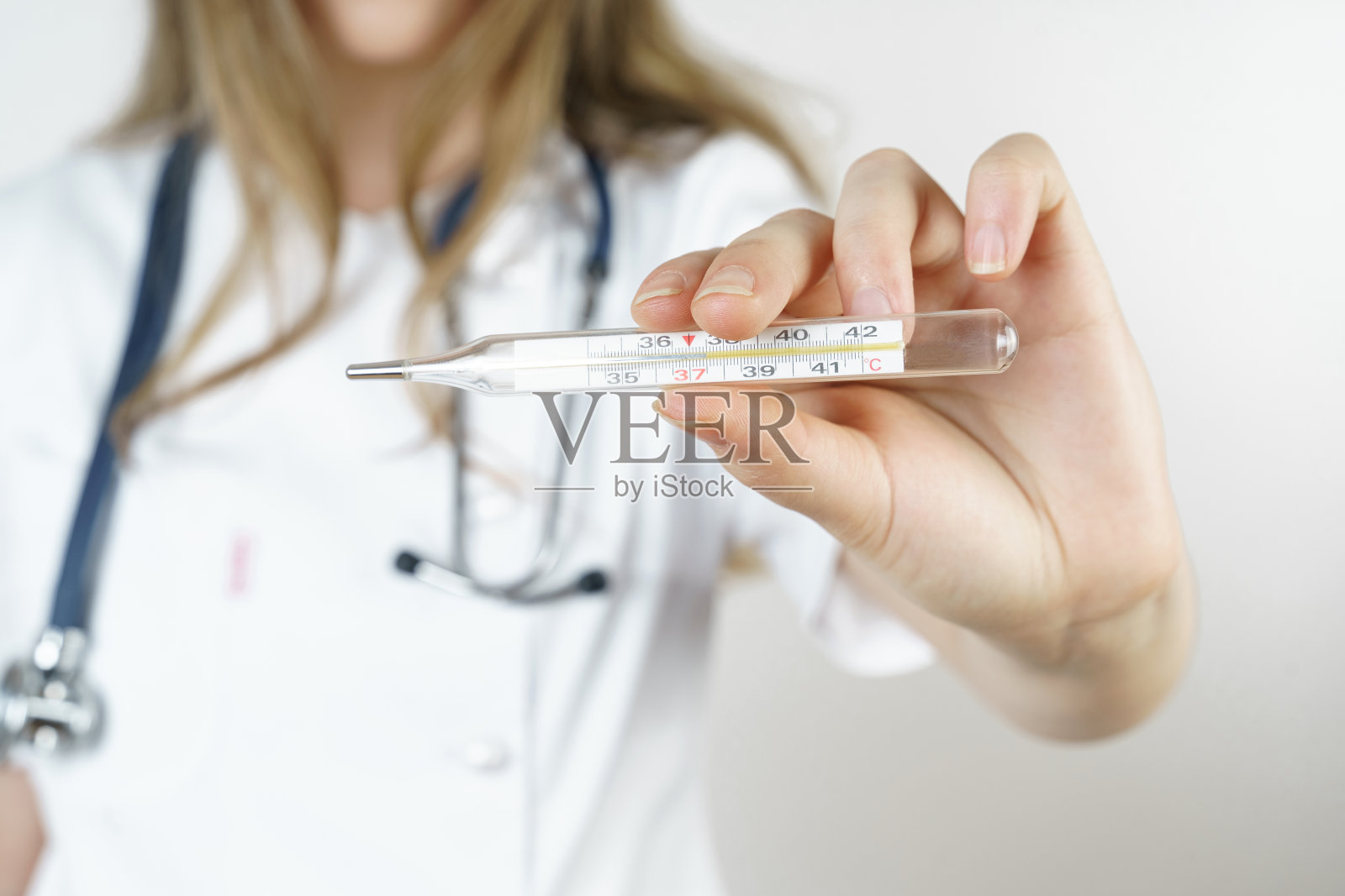 医学健康理念。医生把温度计指给摄像机看。照片摄影图片