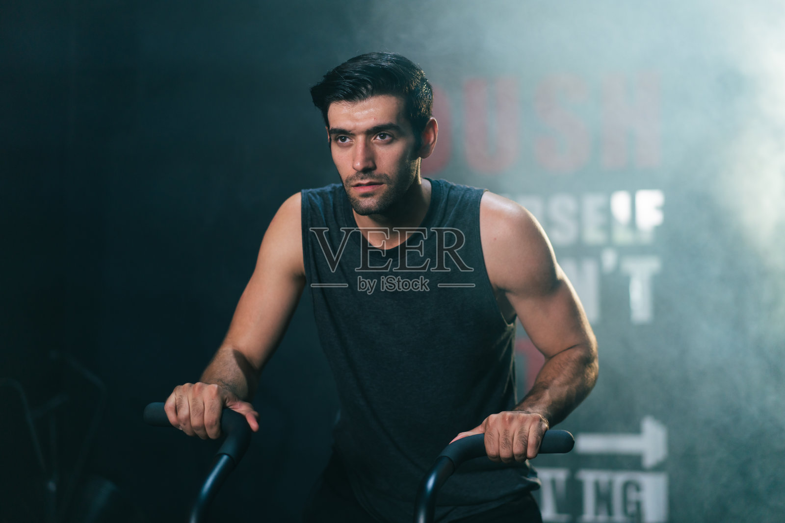 白人男性健身教练在健身房里骑健身自行车锻炼照片摄影图片