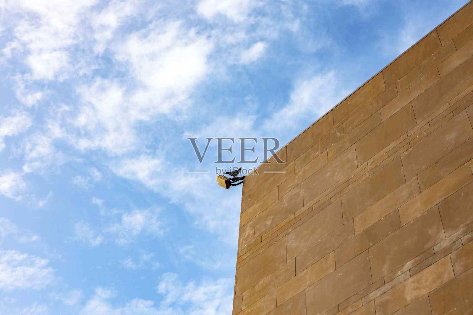 小鸟坐在户外棕色石墙上的灯笼上照片摄影图片