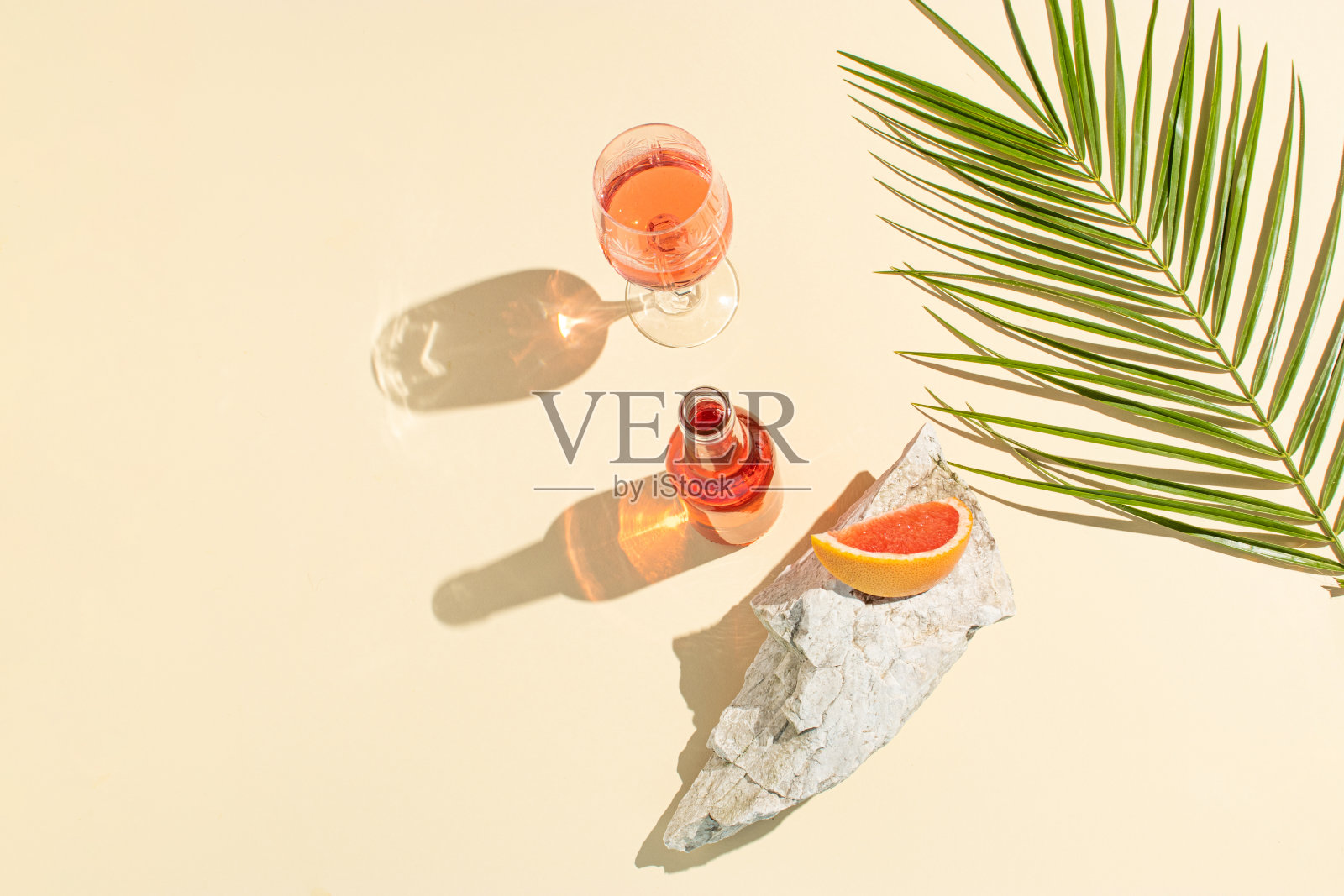 创意的夏季背景与新鲜的鸡尾酒,一个杯子,一块葡萄柚,一个海石和绿色的棕榈枝。夏季,热带,新鲜的鸡尾酒概念。平的。照片摄影图片