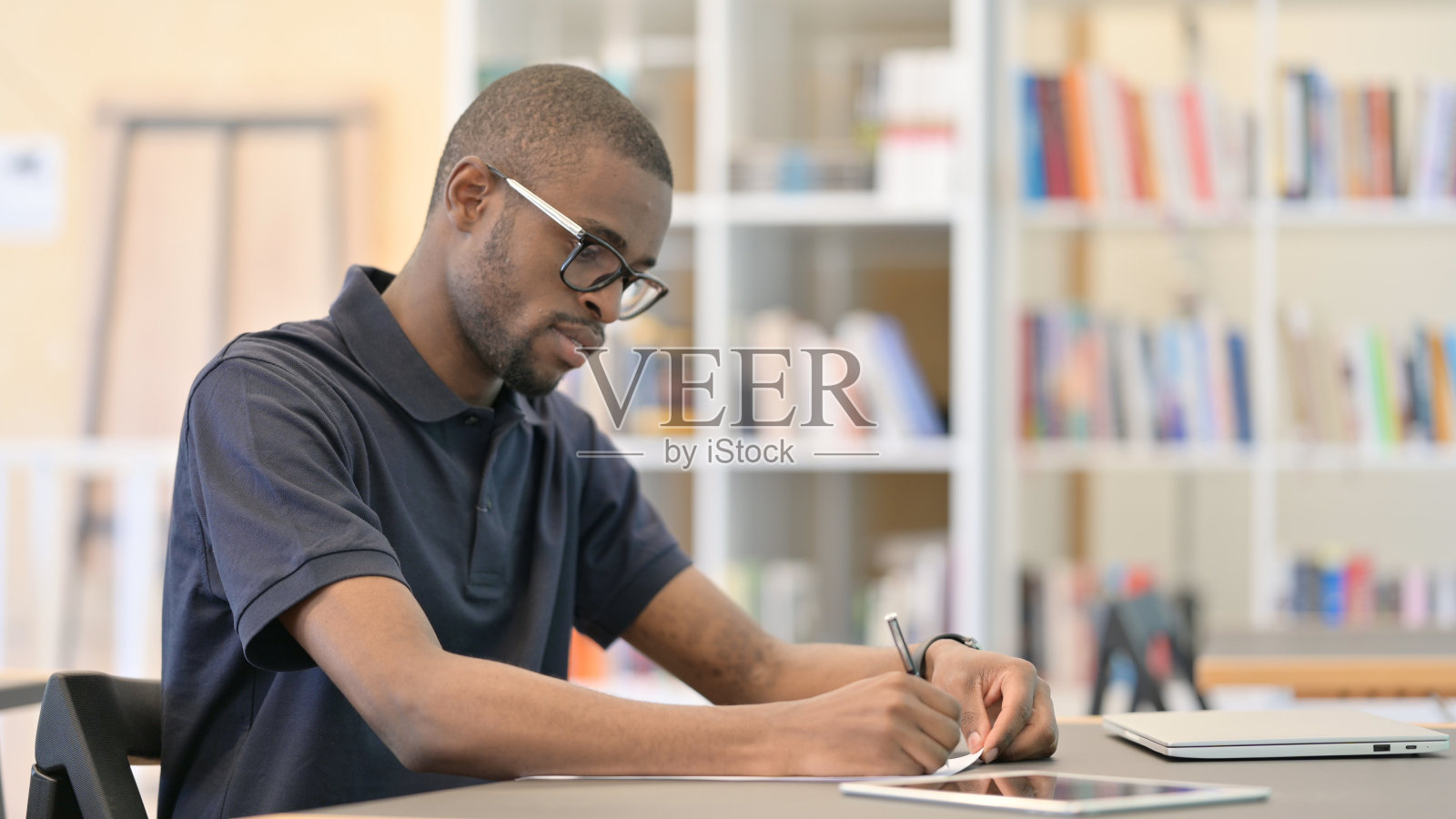 年轻非洲人在图书馆思考和做文书工作照片摄影图片