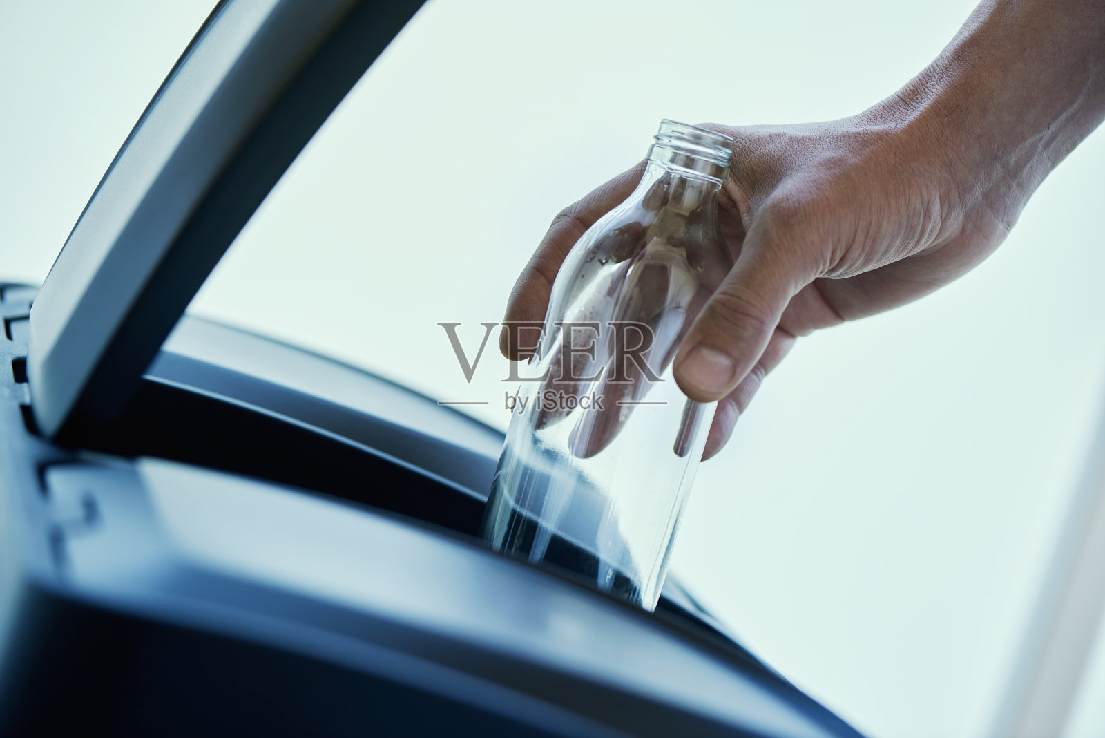 把一个玻璃瓶扔进家里的回收箱照片摄影图片