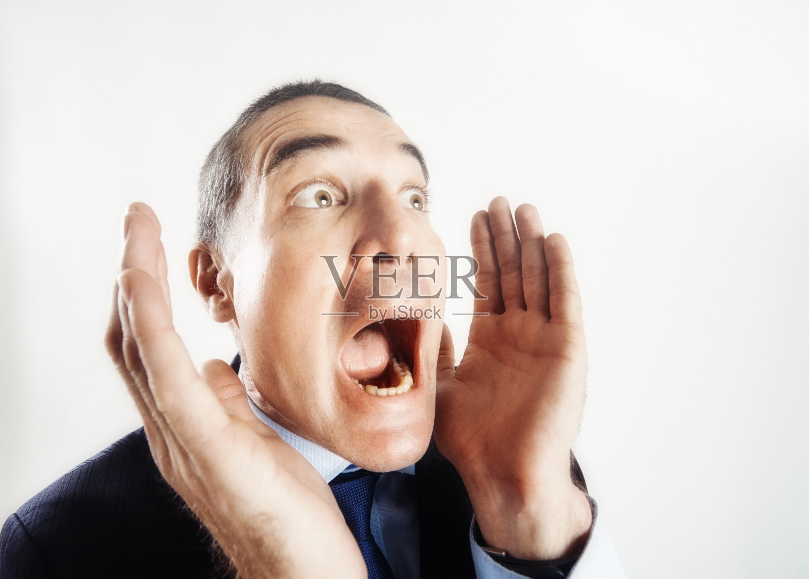 一位穿着西装的商人举起双手,惊恐地尖叫起来照片摄影图片