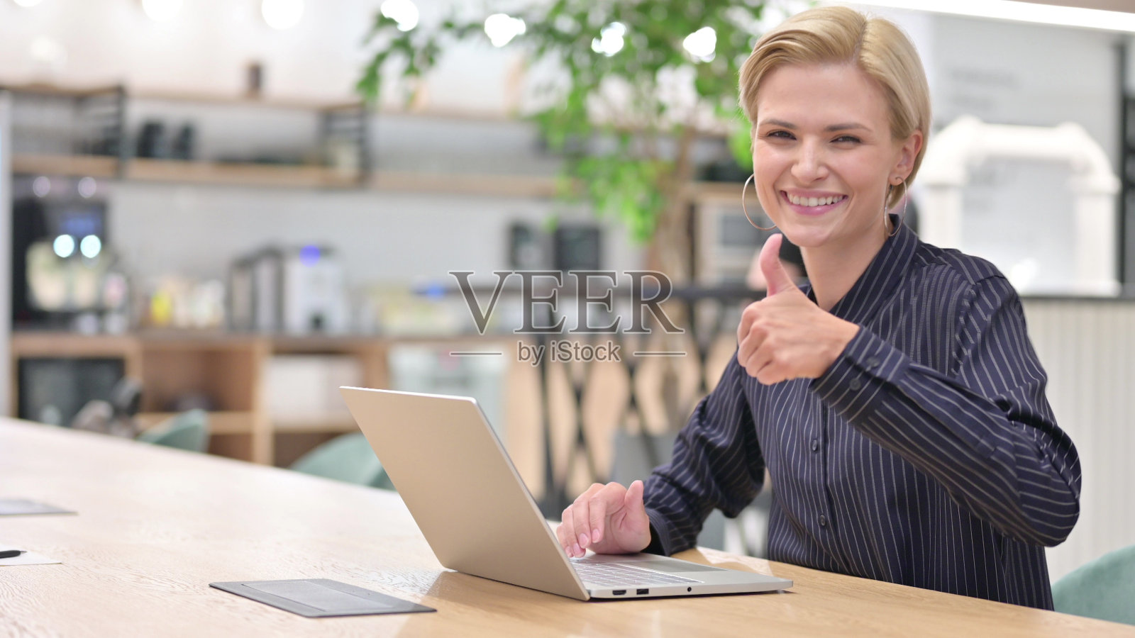 积极的年轻商人拿着笔记本电脑竖起大拇指照片摄影图片