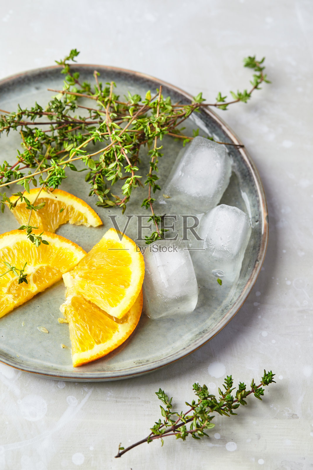 将橘子片、百里香枝和冰块放在盘中,这些都是夏日清凉鸡尾酒或冷茶的配料照片摄影图片