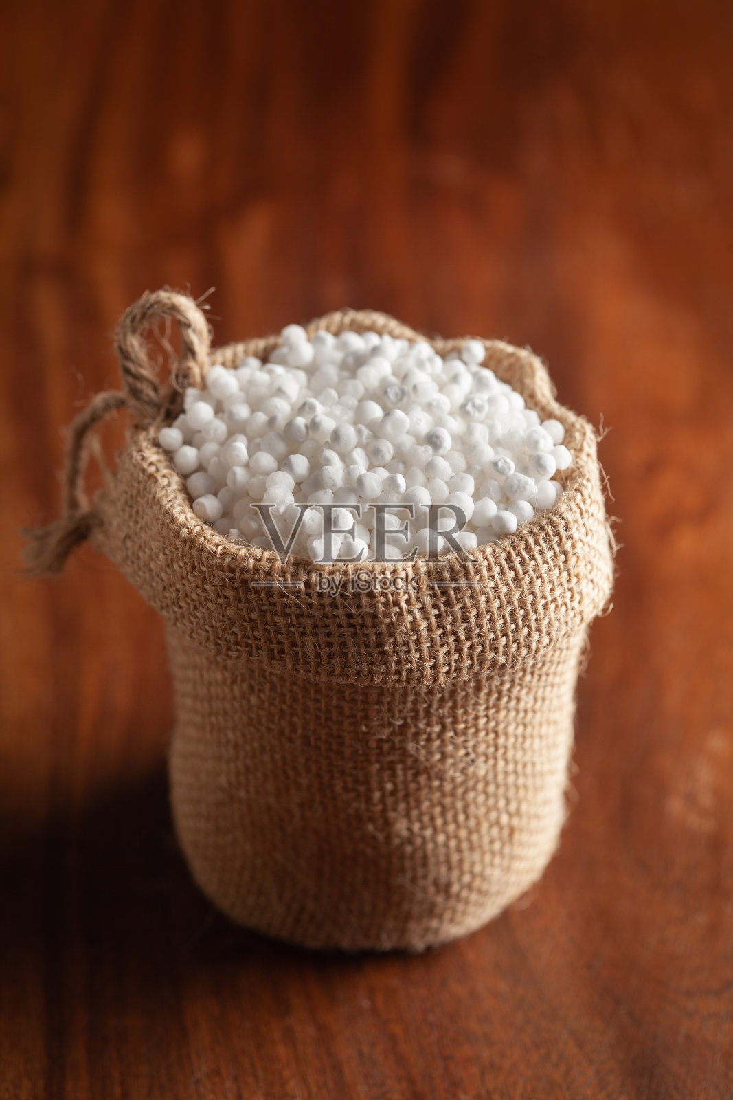 特写的有机白色西米或沙竹大尺寸站在黄麻袋在木制的棕色背景。照片摄影图片