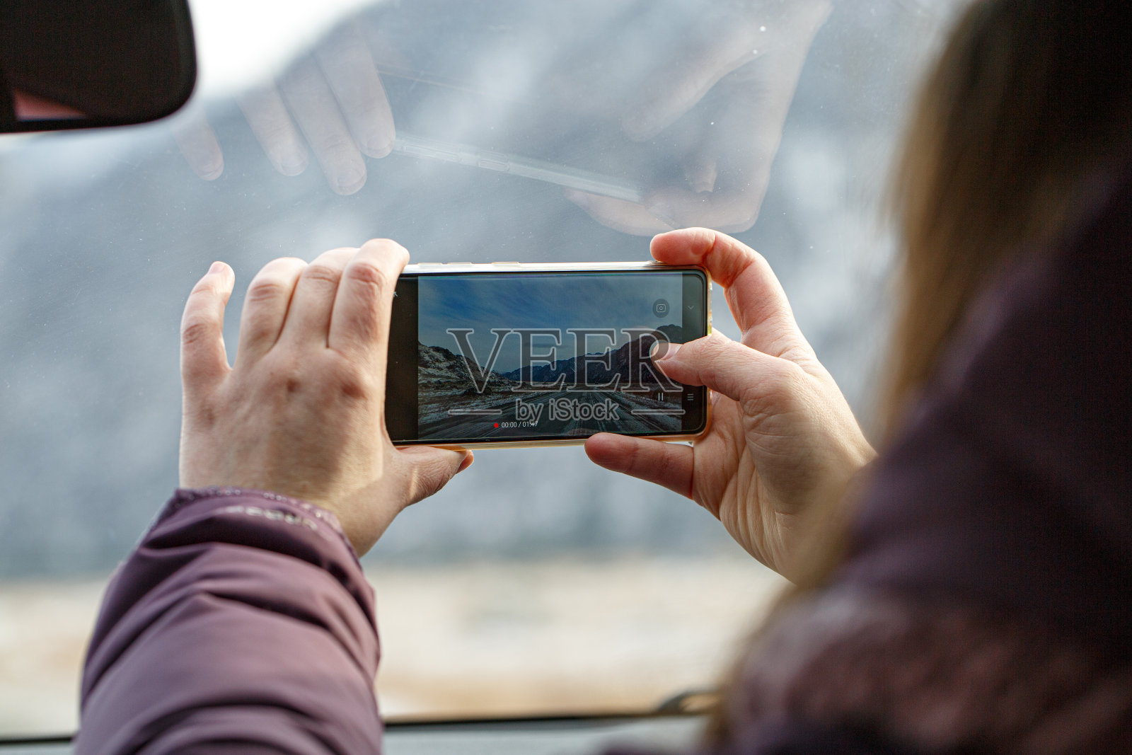 一个女孩在一辆车上用手机录下了一段山路的视频照片摄影图片