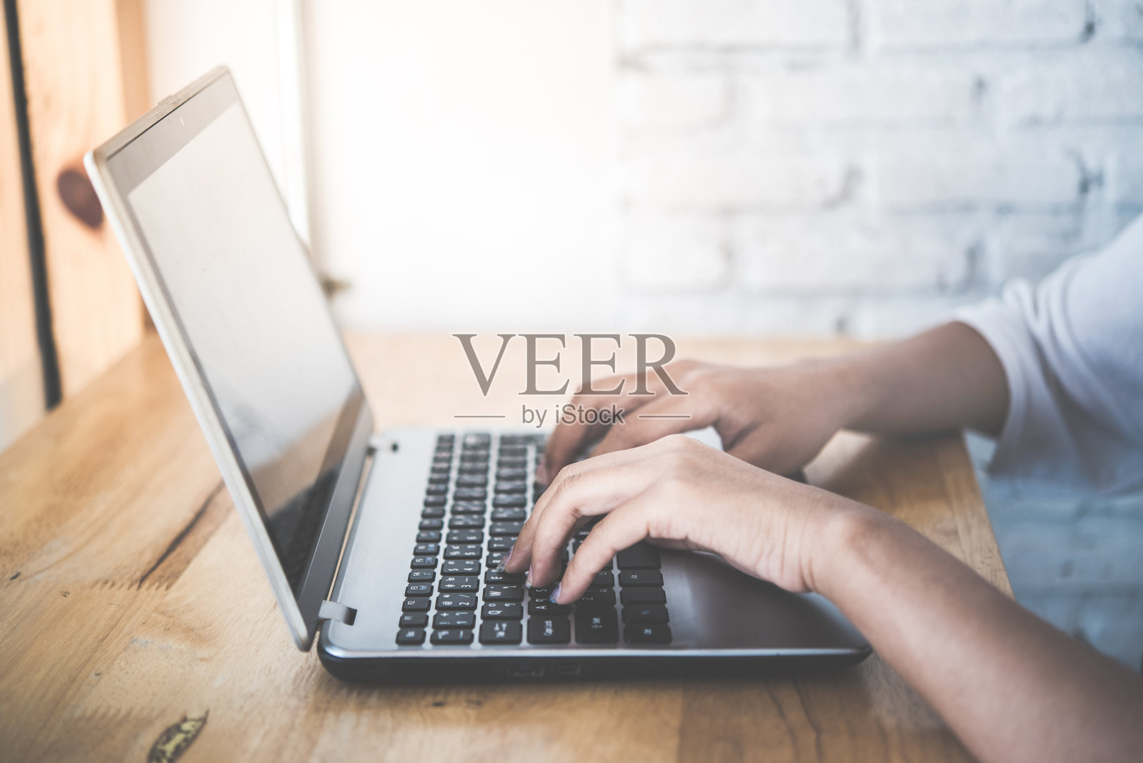 一个女人在咖啡馆的古董木桌上使用笔记本电脑。照片摄影图片