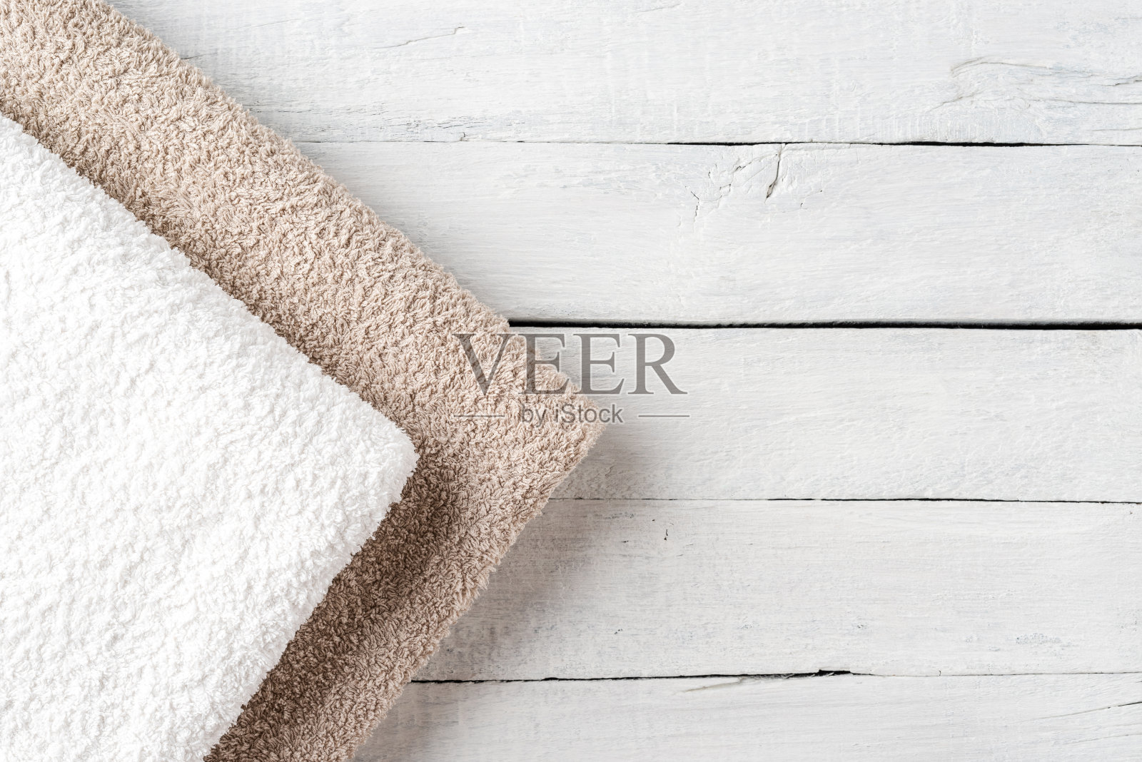 干净的折叠毛巾放在带有复印空间的白色木桌上。俯视图照片摄影图片