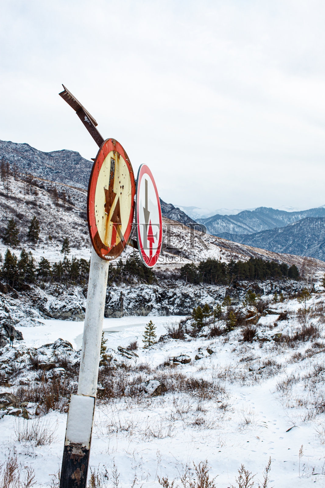 在白雪皑皑的群山背后,老旧的生锈的路标照片摄影图片
