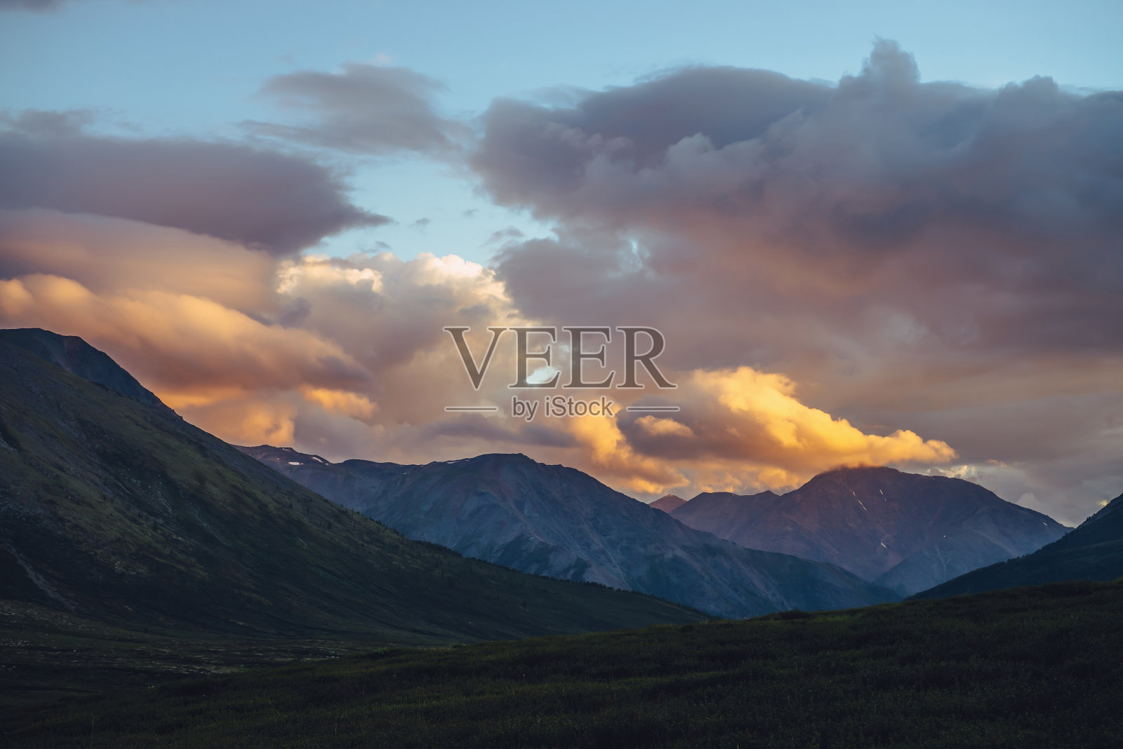 美丽的山景与金色的晨光在多云的天空。风景优美的山川景观,在夕阳的天空中透出斑斓的色彩。日出时群山的剪影。金色照亮天空的阳光照片摄影图片