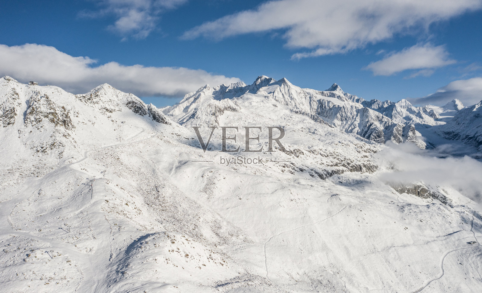 森林的鸟瞰图覆盖着新鲜的雪和云在阿莱奇竞技场地区。秋天的瑞士照片摄影图片